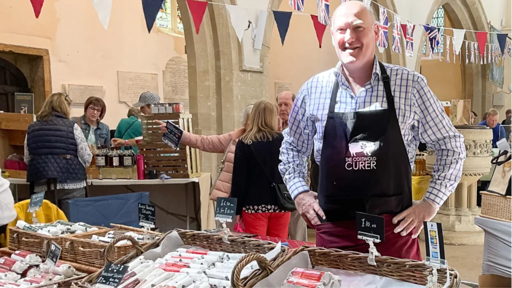 A smiling stallholder in an apron behind his stall inside St Mary’s