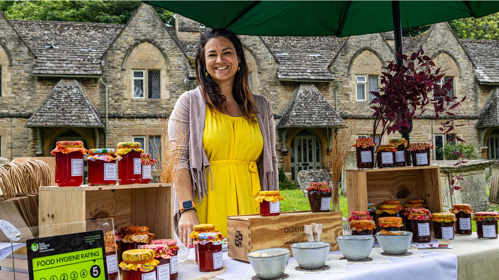 A stallholder in a yellow dress selling homemade chutneys and preserves at a stall in front of St Mary's Church, Witney, at the Witney Festival of Food and Drink